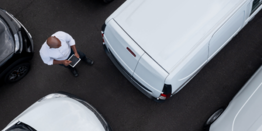 Overhead view of a person holding a tablet standing between parked commercial vehicles in North Dakota, related to personal injury attorney