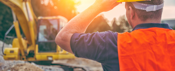 Construction worker standing in front of heavy machinery