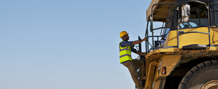 Worker climbing machinery on site