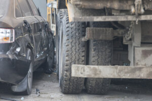 A truck run into the sidewalk and crush the car.